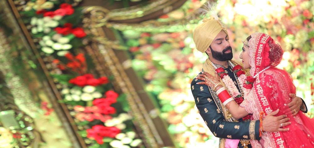 a bride and groom embracing in front of a floral wall