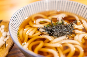 a bowl of soup with noodles and seaweed
