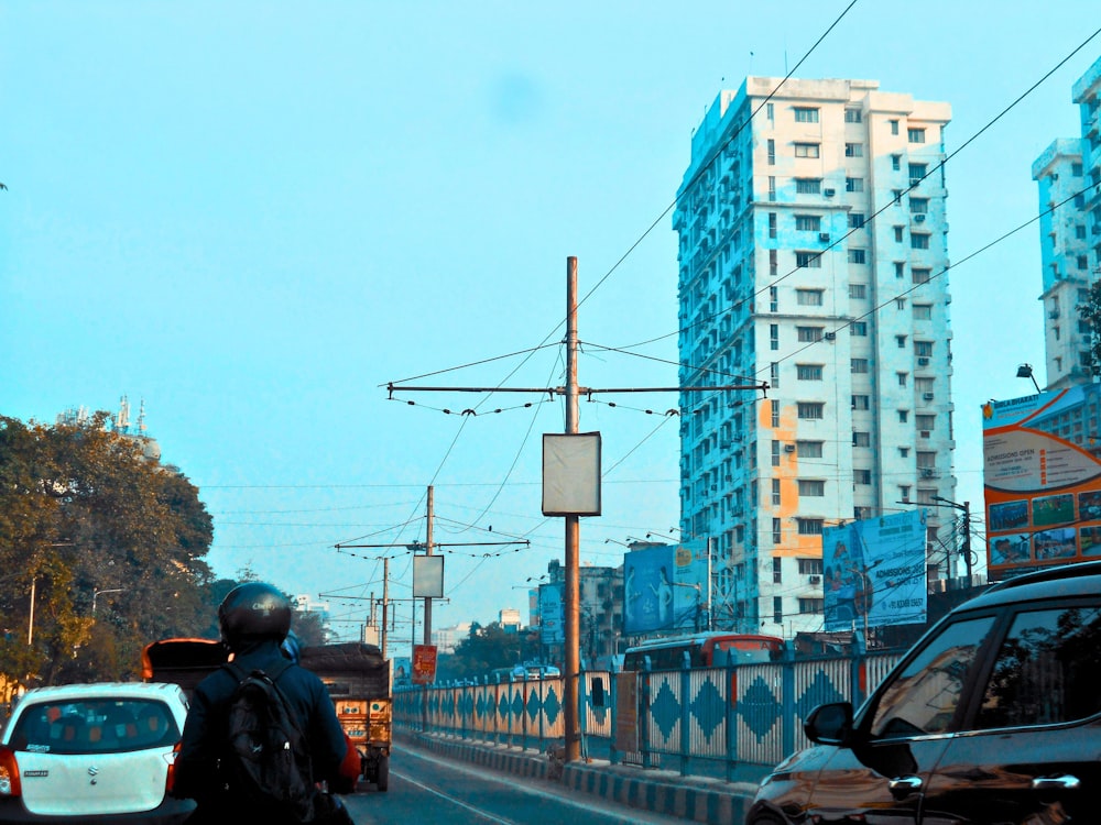 a man riding a motorcycle down a street next to tall buildings