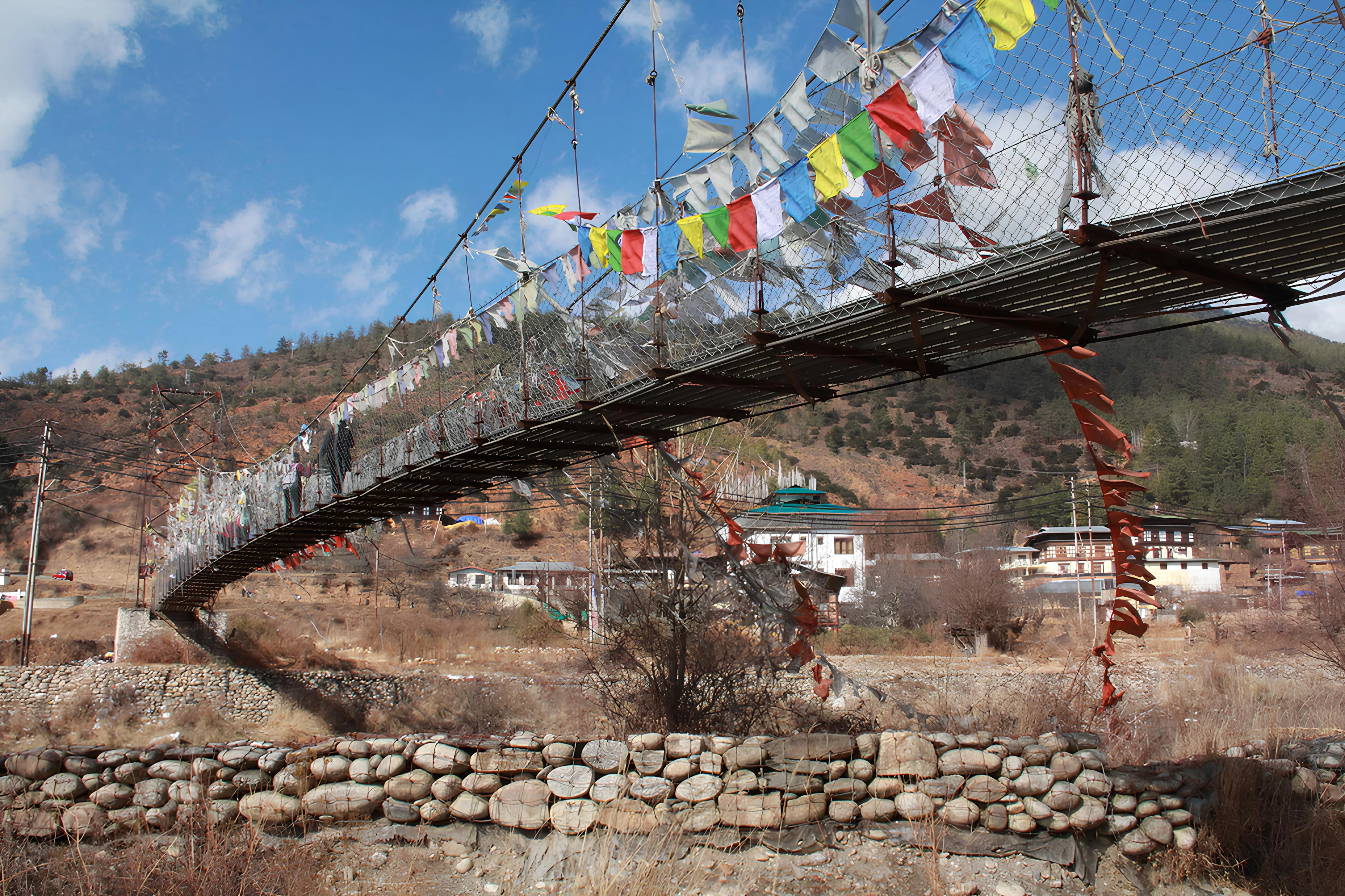 Suspension bridge draped in colourful prayer flags in the mountains of Bhutan