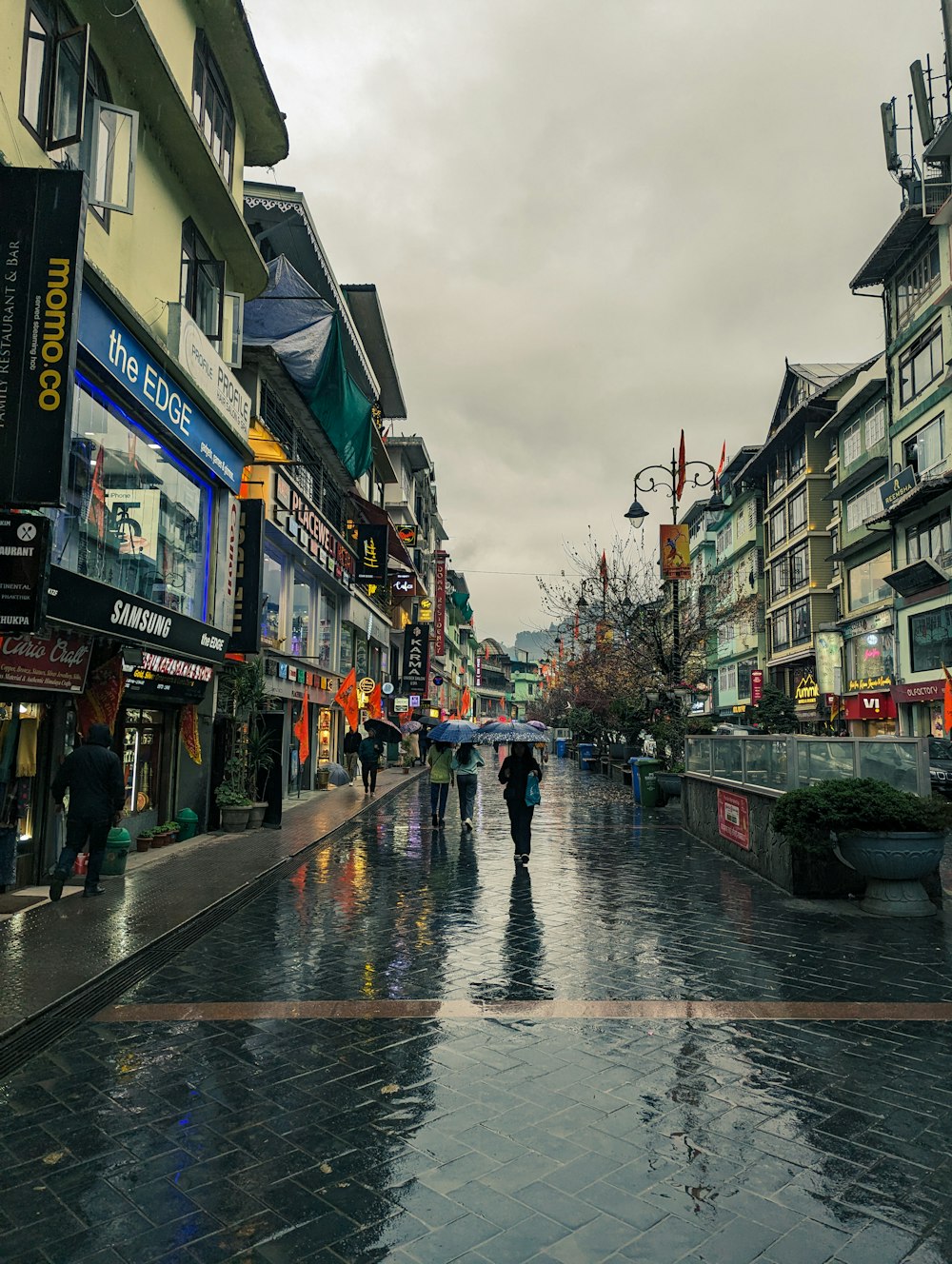 a group of people walking down a street holding umbrellas