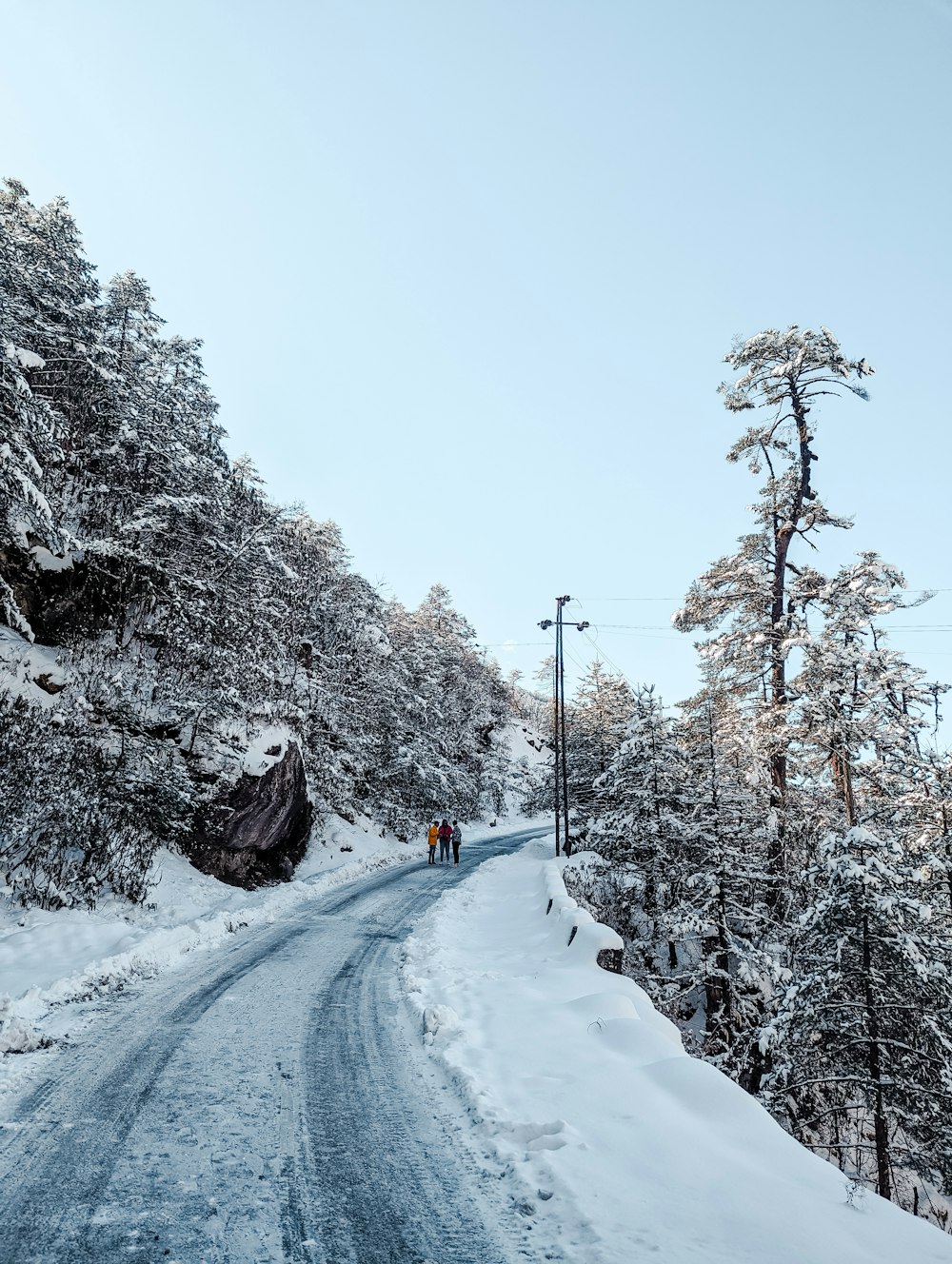 a couple of people walking down a snow covered road