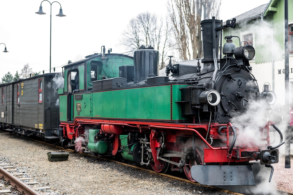 a green and red train traveling down train tracks