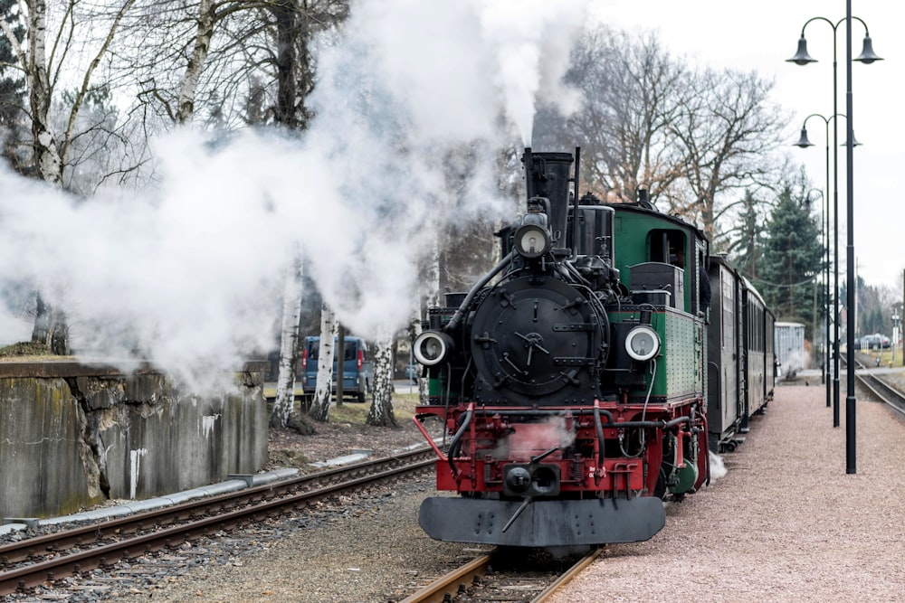 a steam train traveling down train tracks next to a forest