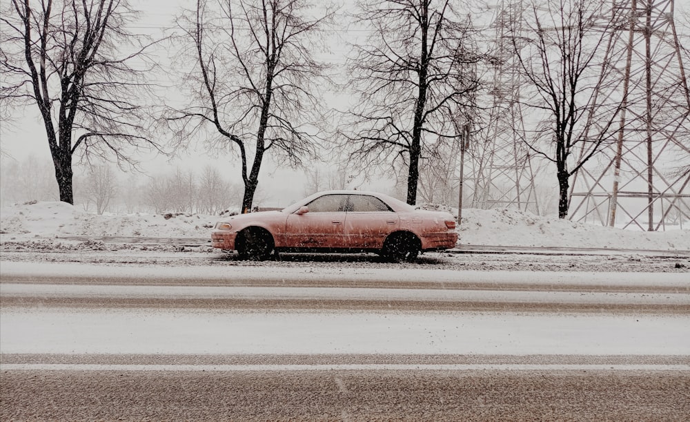 a red car is parked on a snowy road