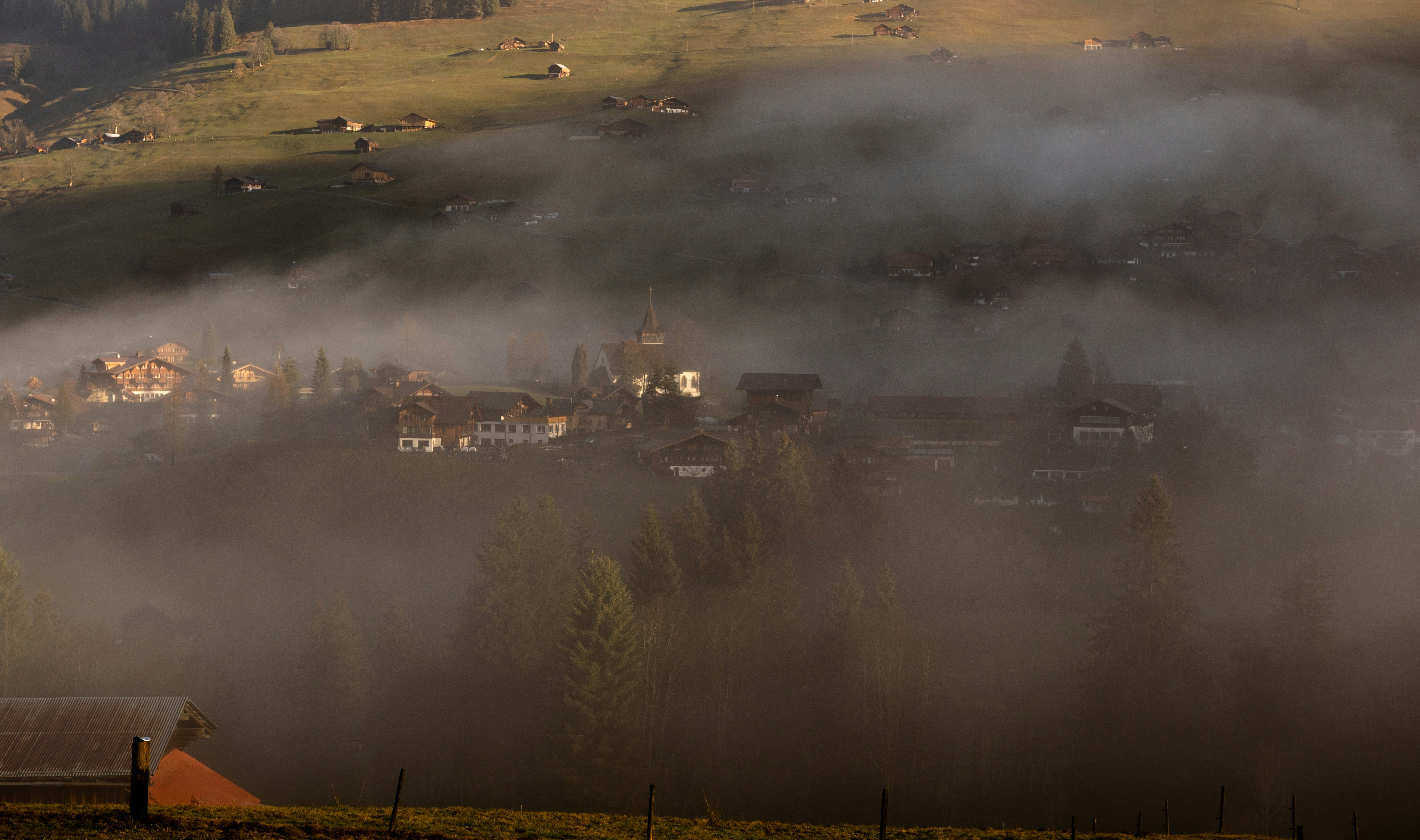 a foggy valley with a village in the distance
