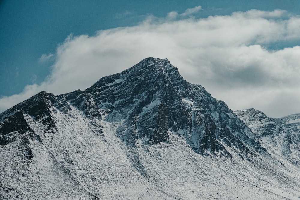 a snow covered mountain under a cloudy blue sky