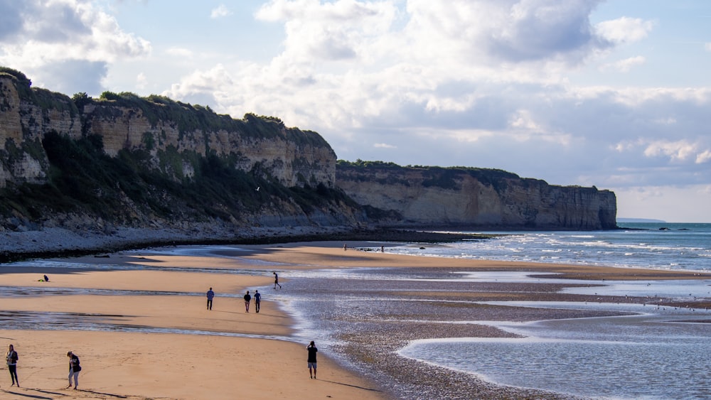 a group of people standing on top of a sandy beach