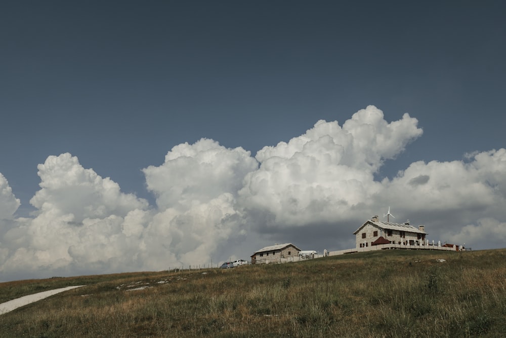 una casa seduta in cima a una collina sotto un cielo nuvoloso