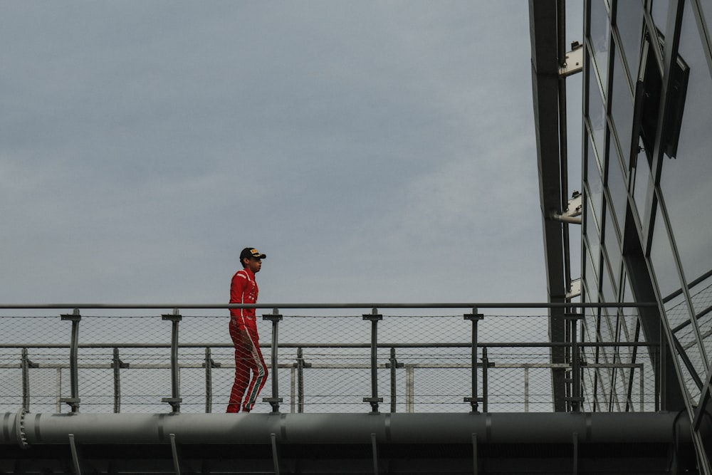 a man in a red suit walking across a bridge