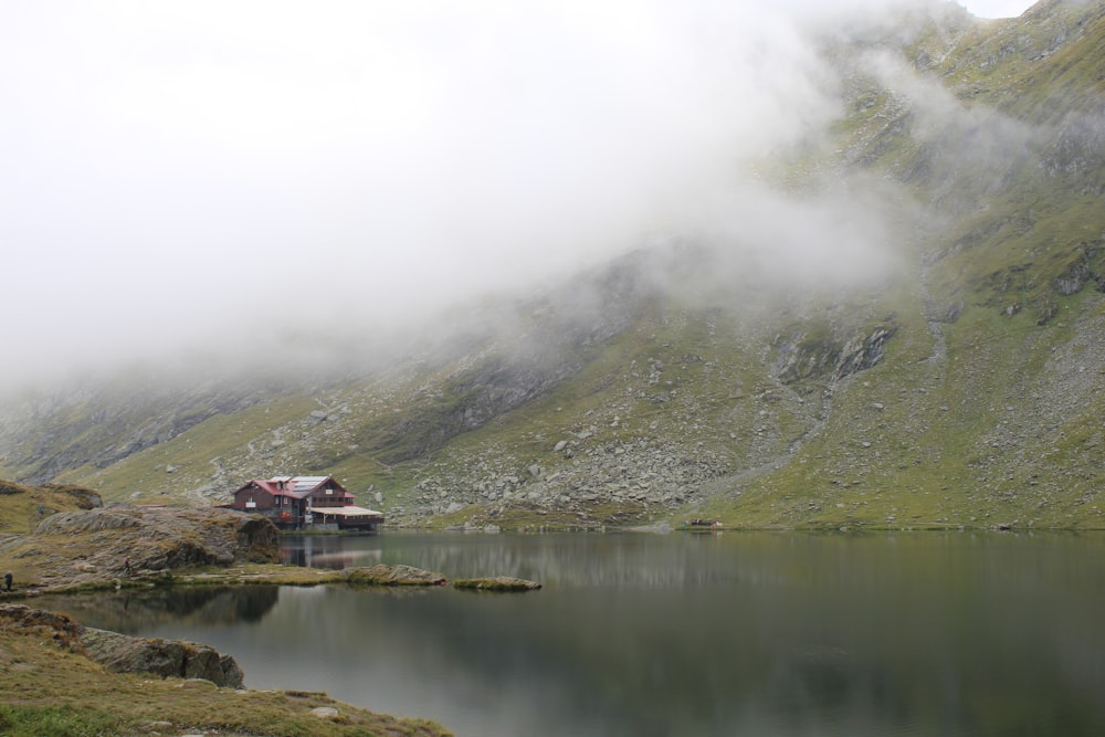 a house sitting on top of a mountain next to a lake