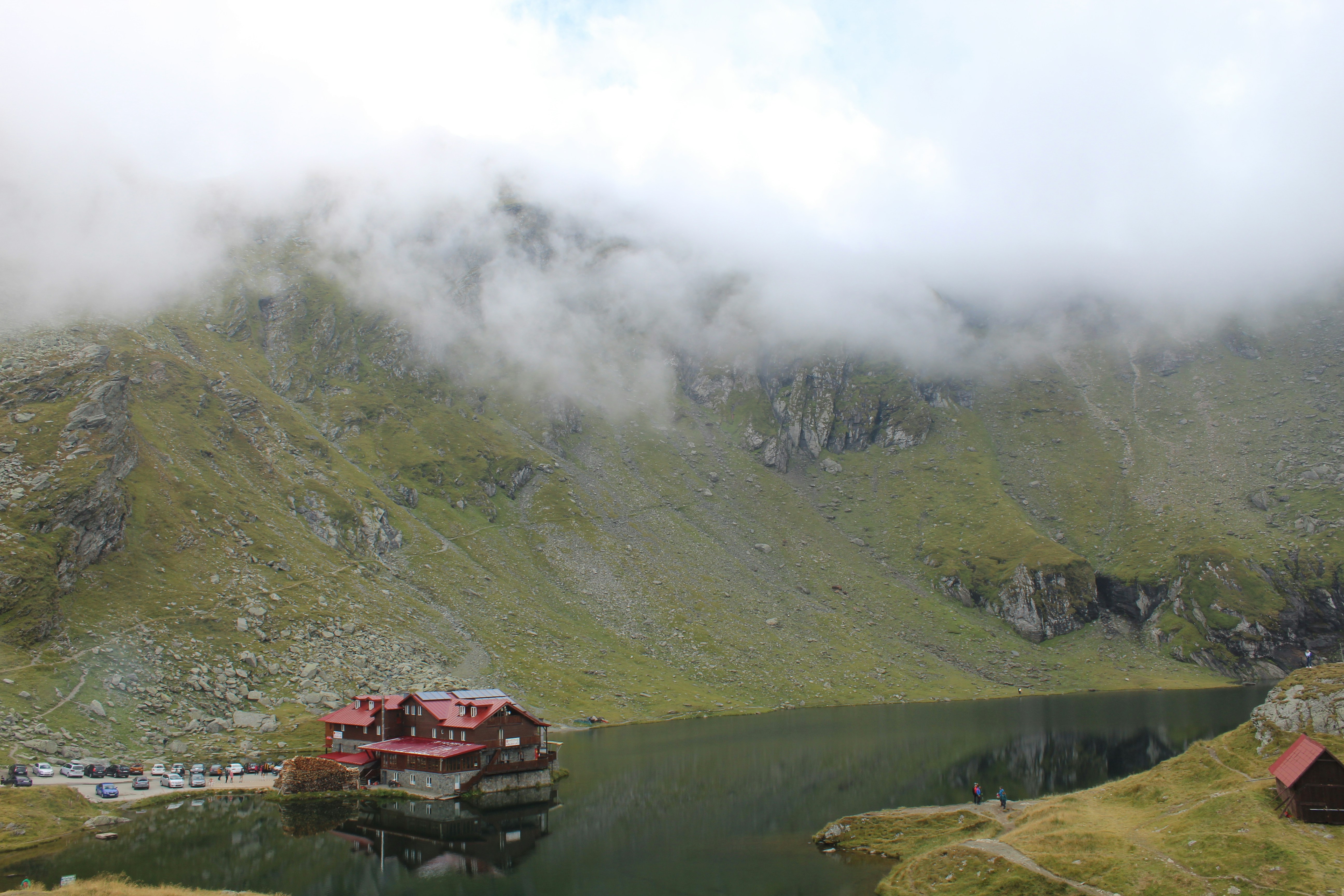 a house in the middle of a lake surrounded by mountains