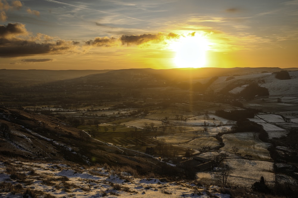 the sun is setting over a snowy landscape