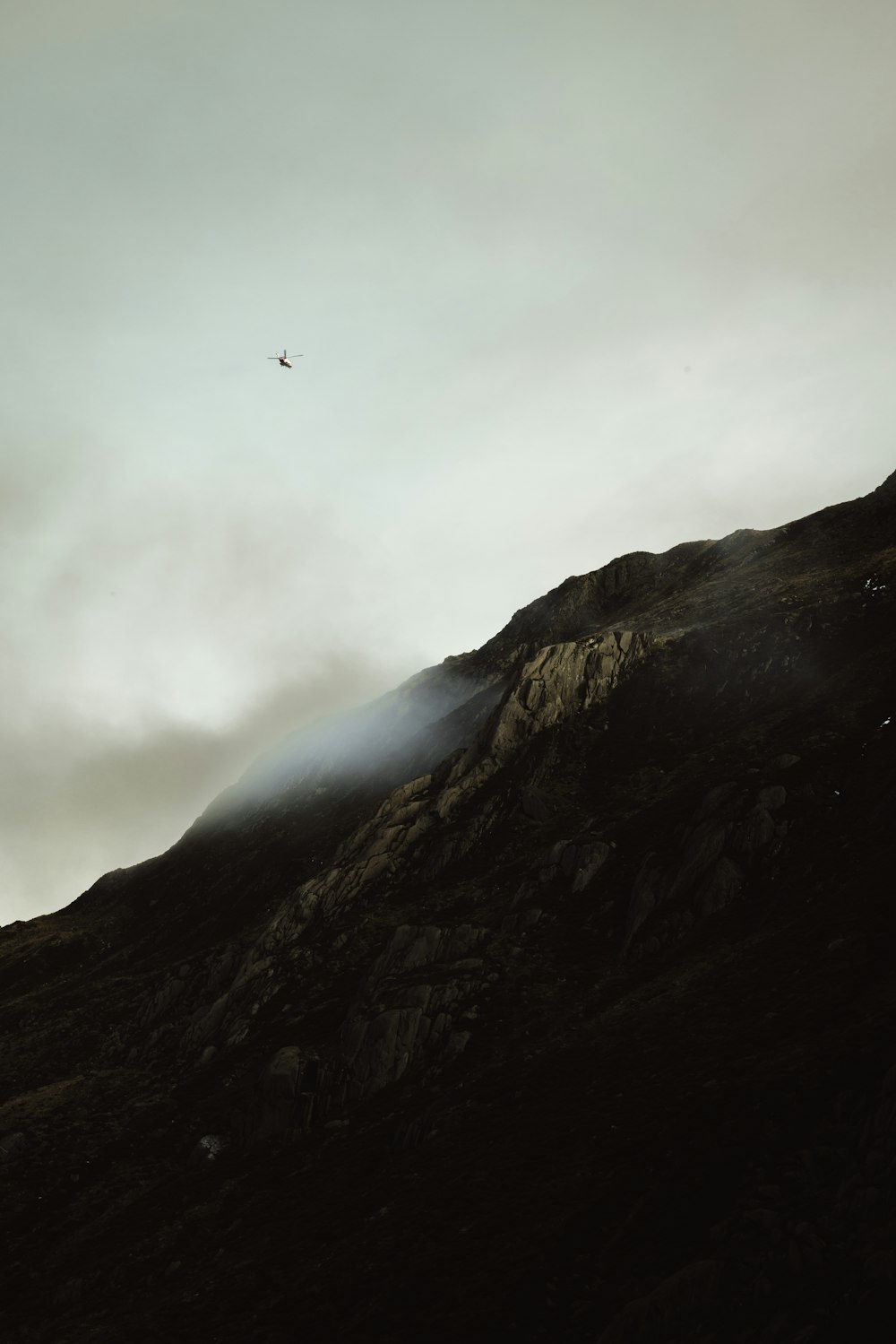 a plane flying over a mountain on a cloudy day