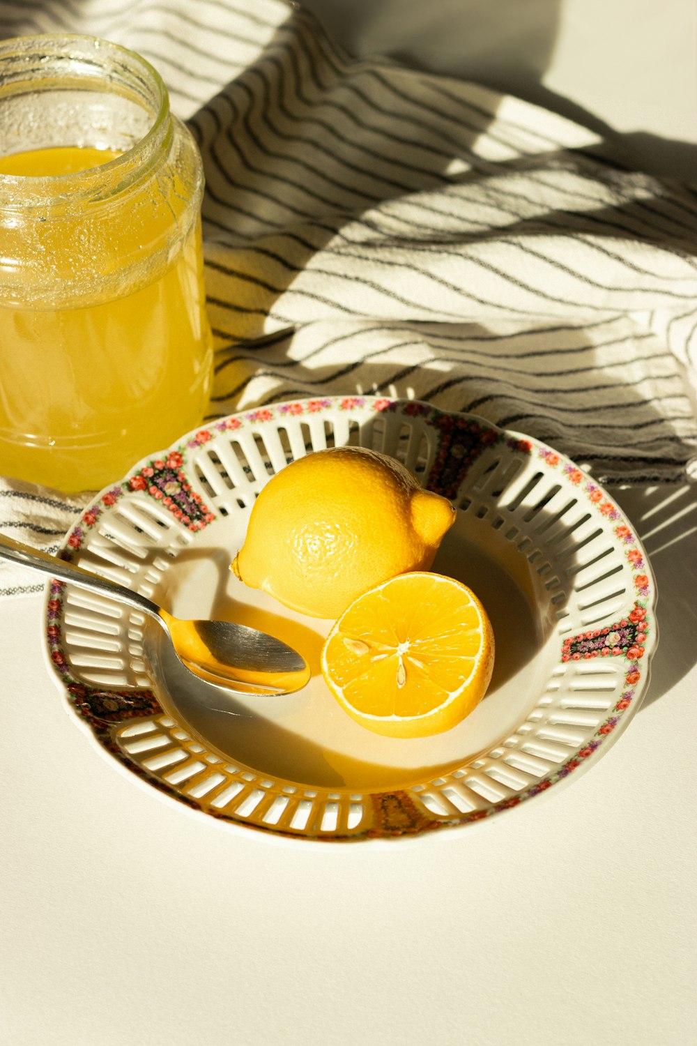 uma tigela de limões e um pote de mel sobre uma mesa