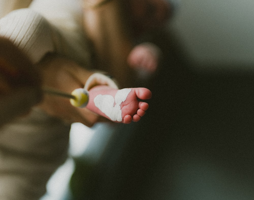 a person holding a baby's foot with a heart cut out of it