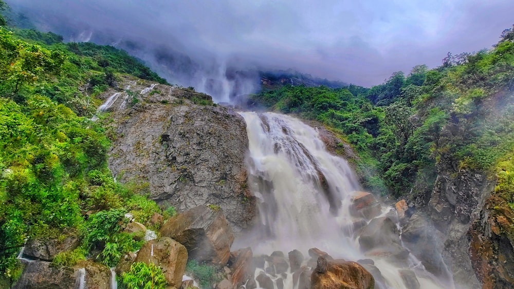 a large waterfall surrounded by lush green trees