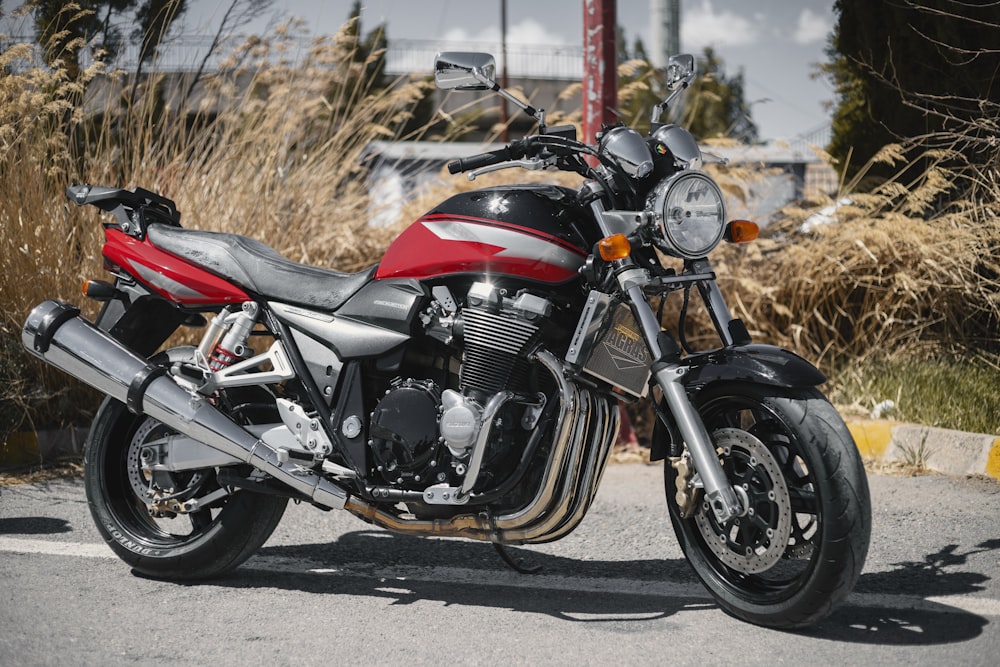 a red and black motorcycle parked on the side of the road