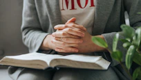 a person sitting down with their hands folded over a book