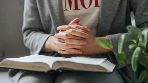 a person sitting down with their hands folded over a book