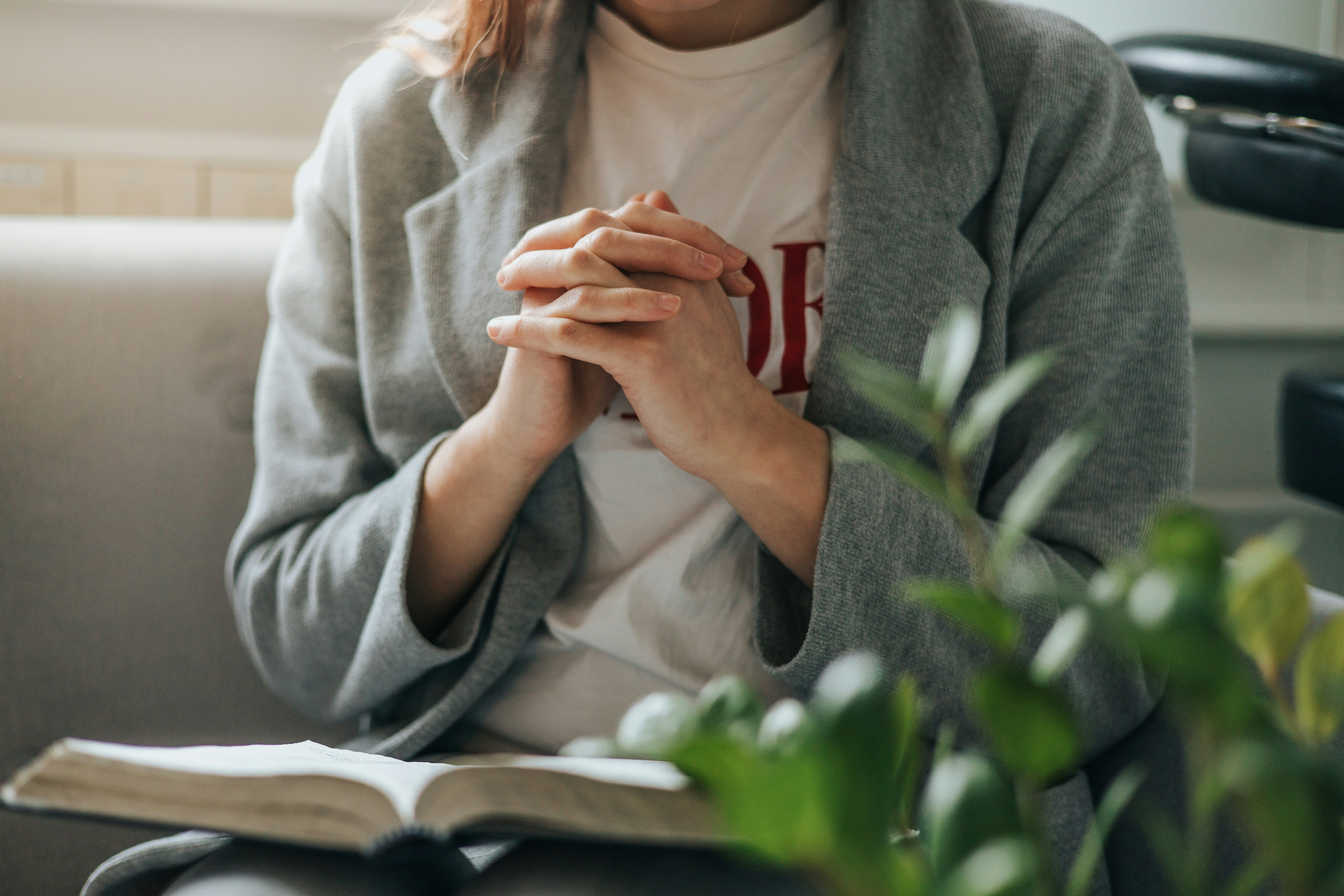 a woman sitting on a couch holding her hands together
