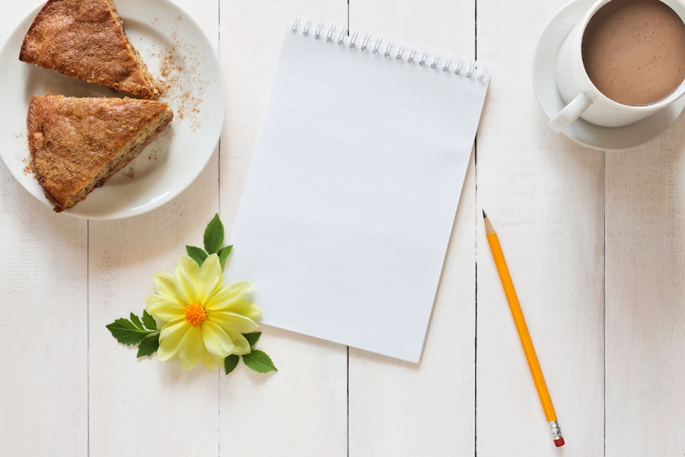 a piece of pie next to a cup of coffee and a pencil