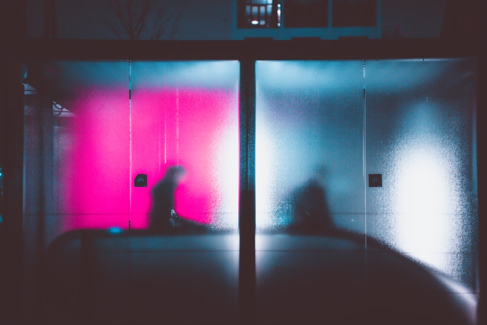 a person standing in front of a pink and blue wall