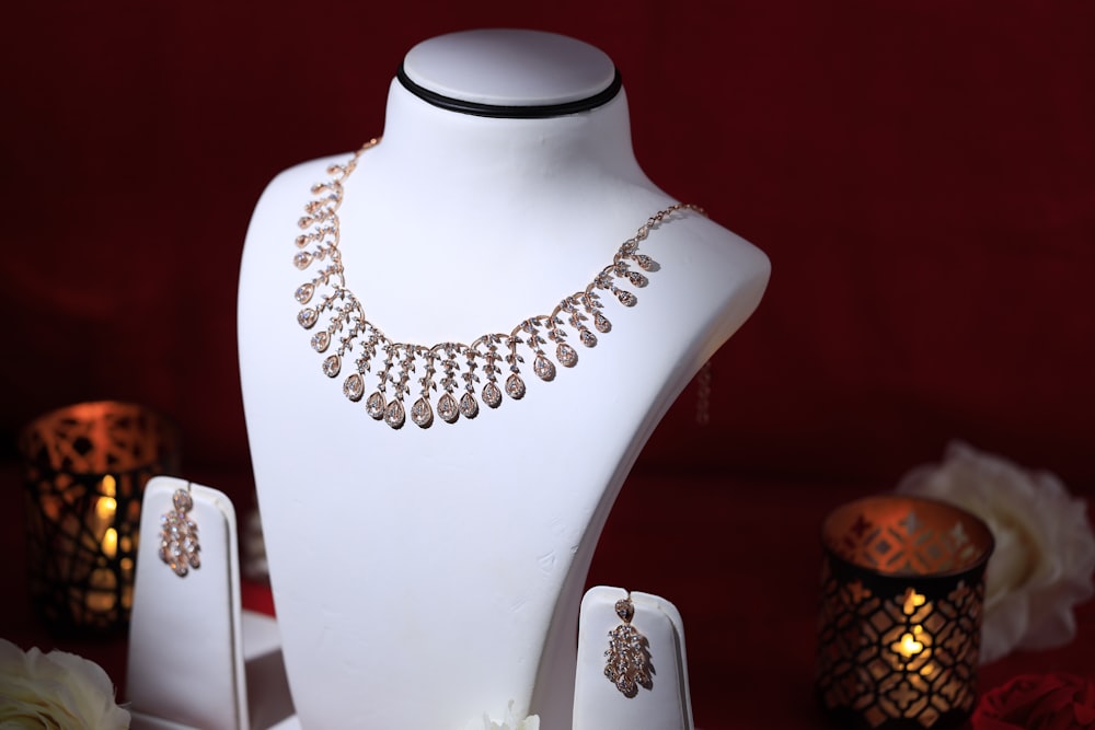 a white mannequin with a necklace and earrings on it