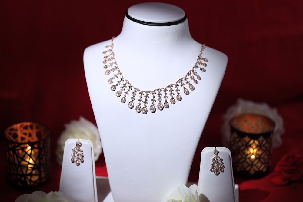 a white mannequin with a necklace and earrings on it