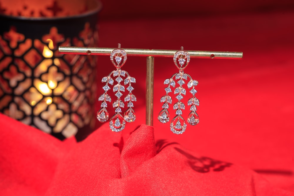 a pair of diamond earrings on a red cloth