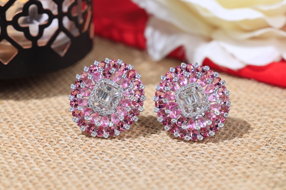 a pair of pink and white earrings sitting on top of a table