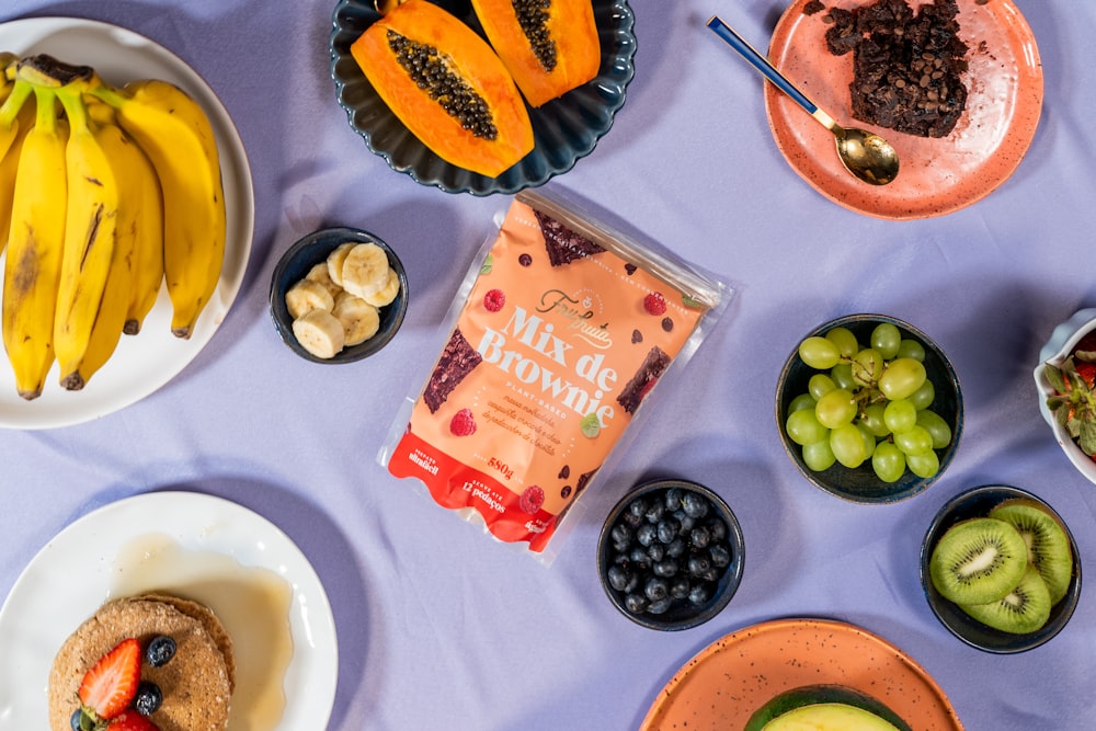 a table topped with plates of food and bowls of fruit