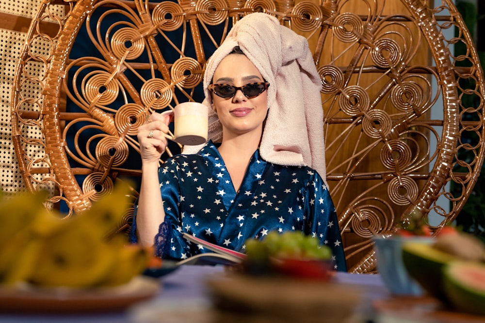 eine Frau mit einem Handtuch auf dem Kopf, die eine Tasse Kaffee trinkt