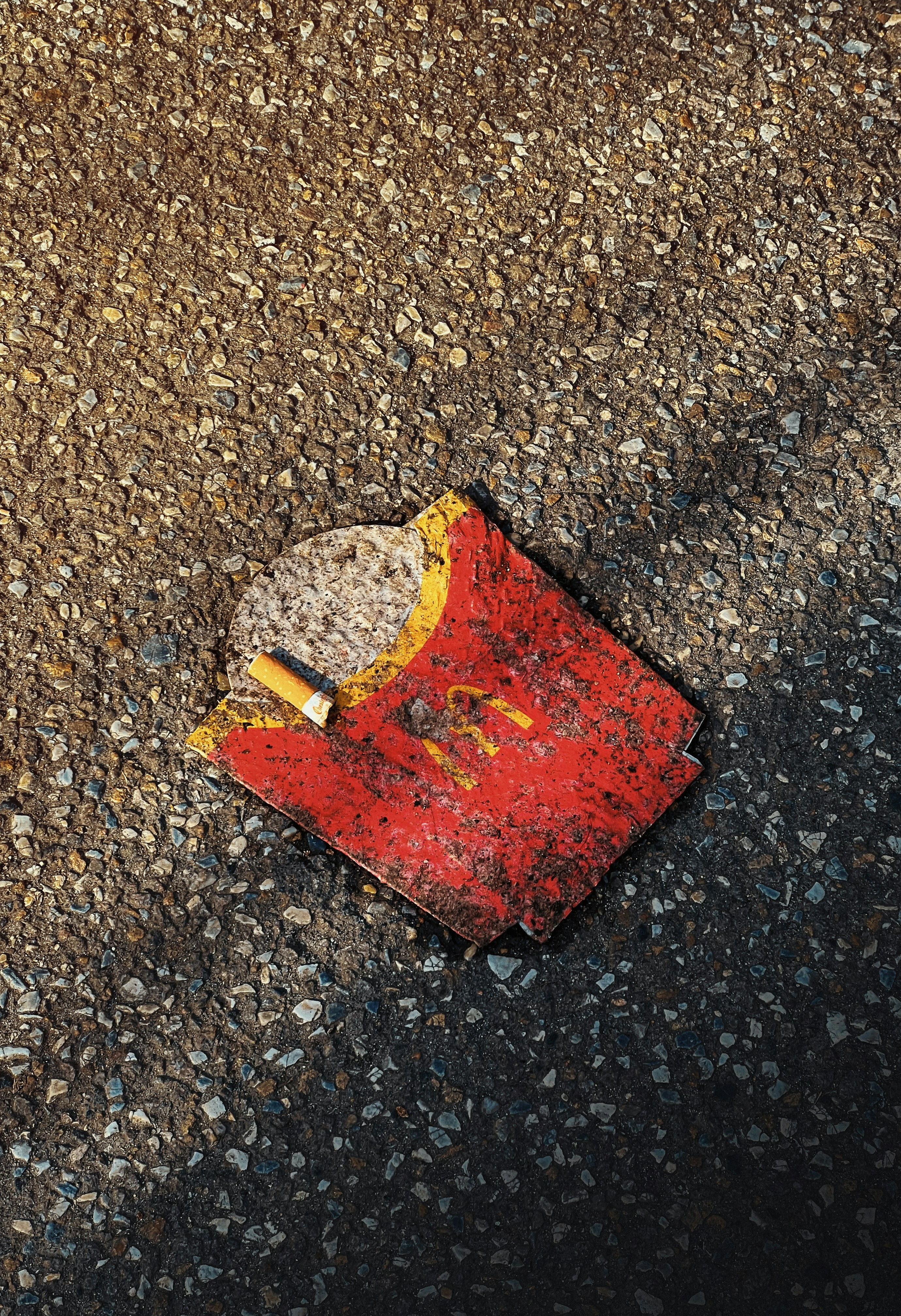 A person looking tired and unhappy, sitting at a table with fast food wrappers.