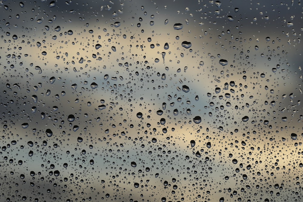 rain drops on a window with a cloudy sky in the background