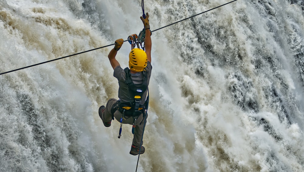 a man on a rope above a waterfall