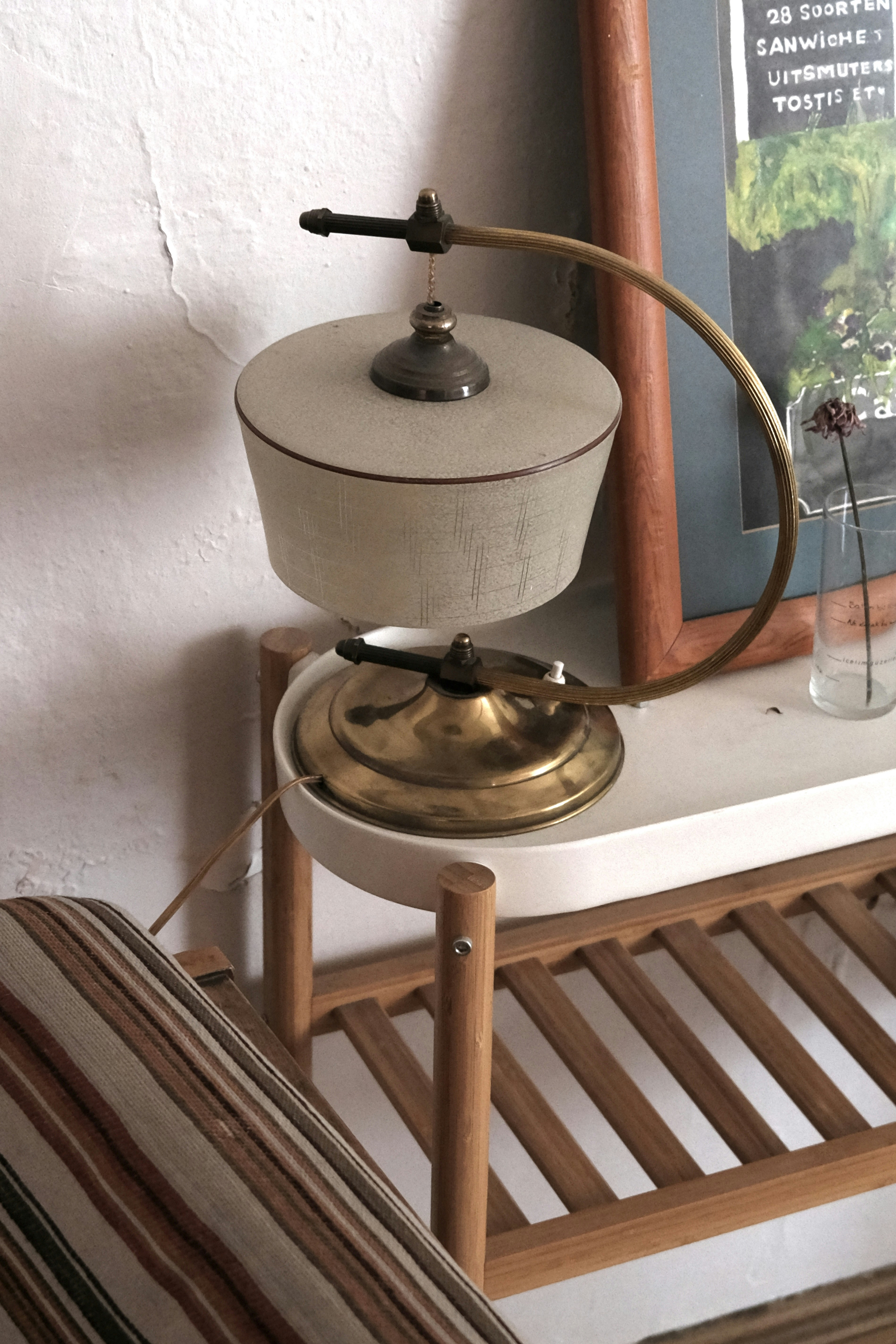 Vintage brass table lamp with white shade glowing warmly on dark wood desk