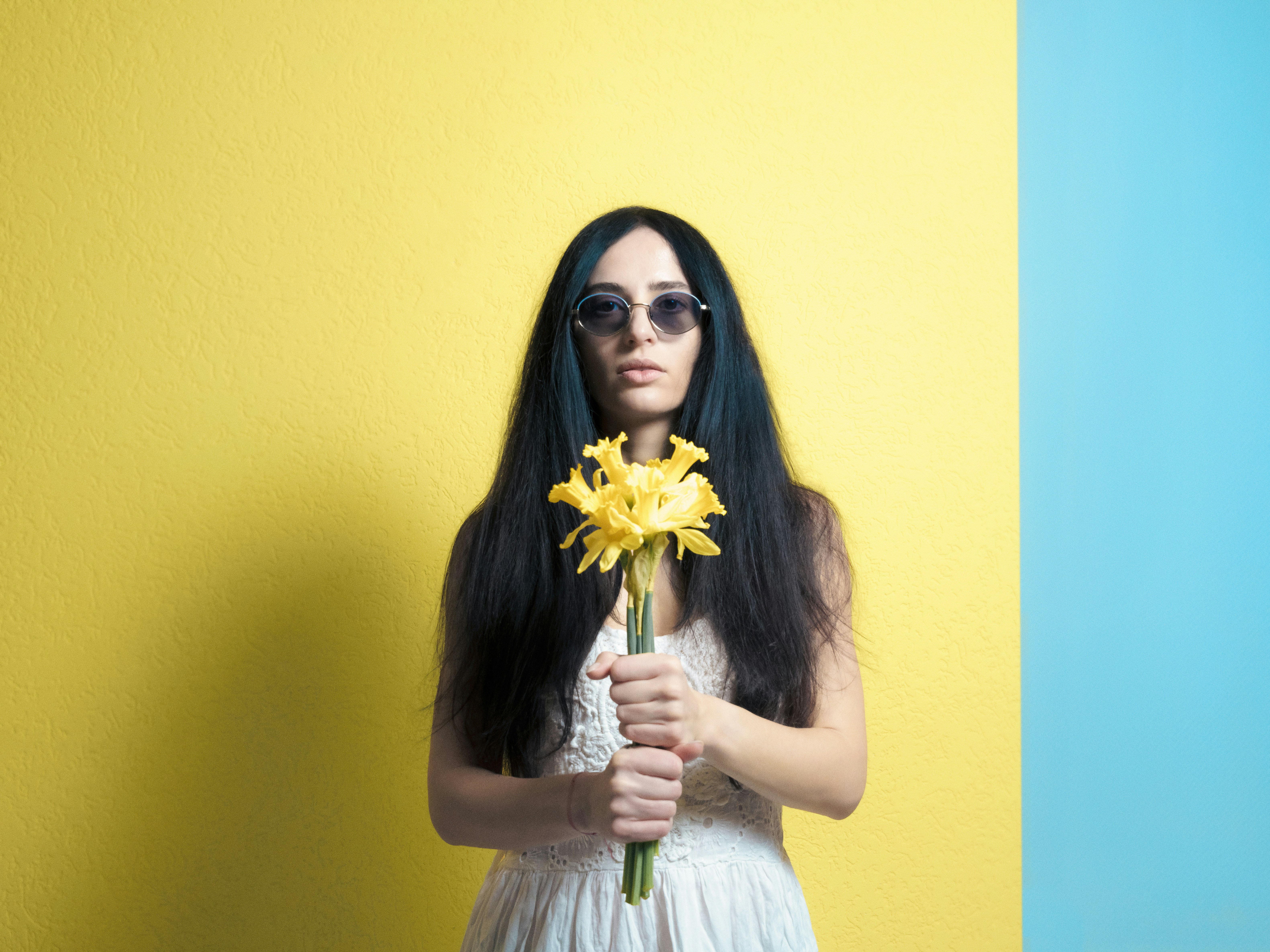 a woman with long black hair holding a yellow flower