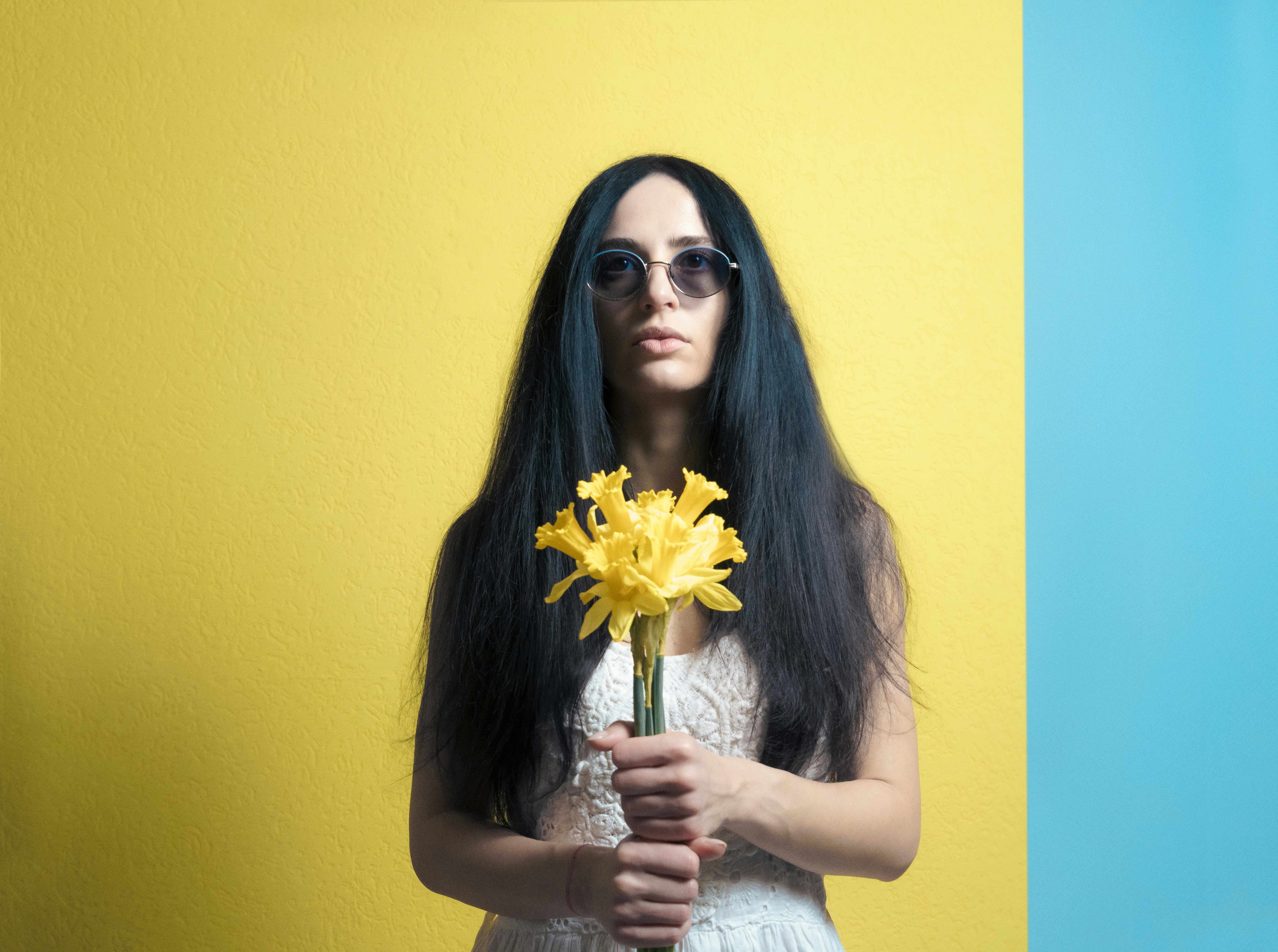 a woman with long black hair holding a yellow flower