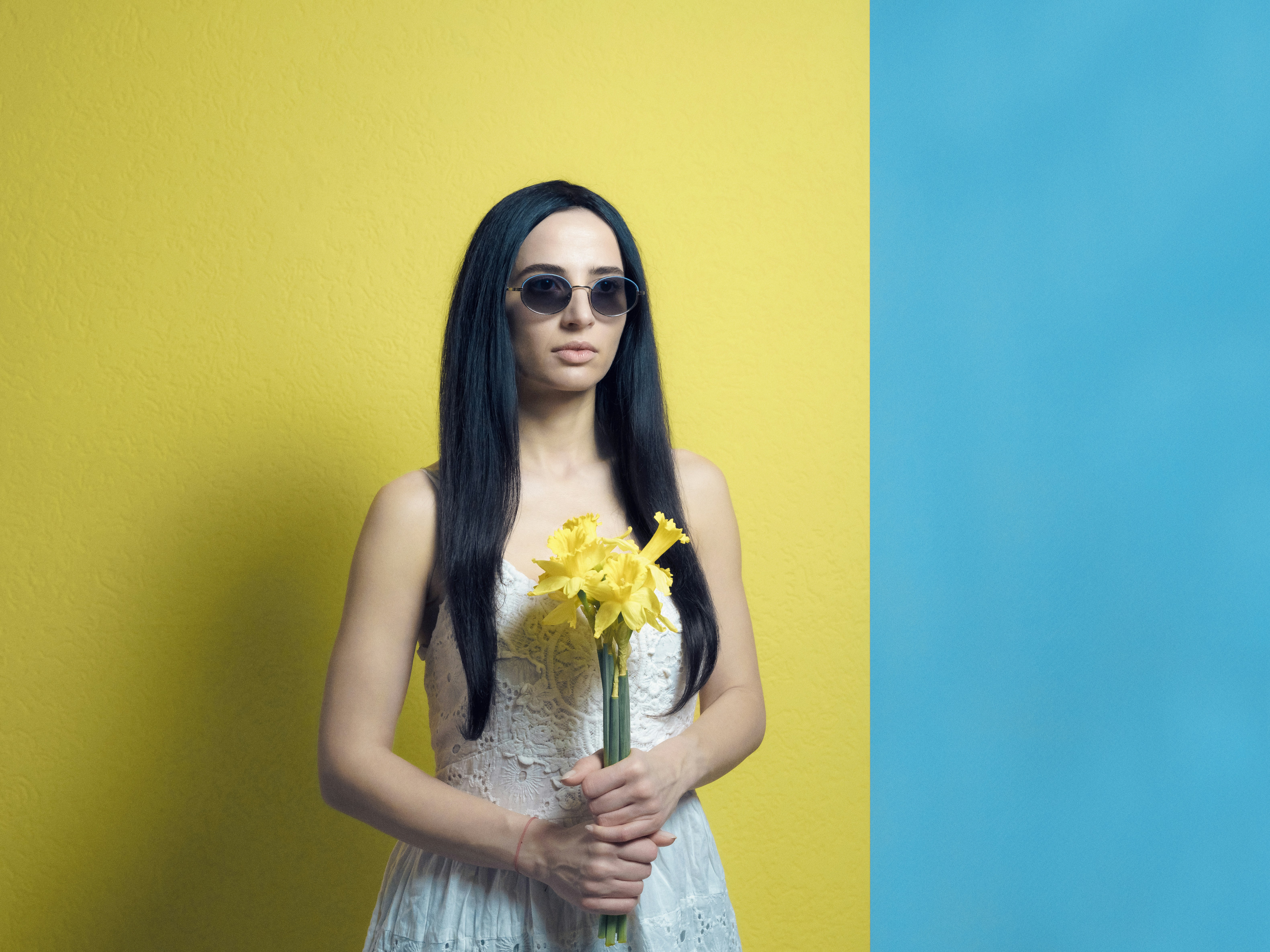 a woman in a white dress holding a yellow flower