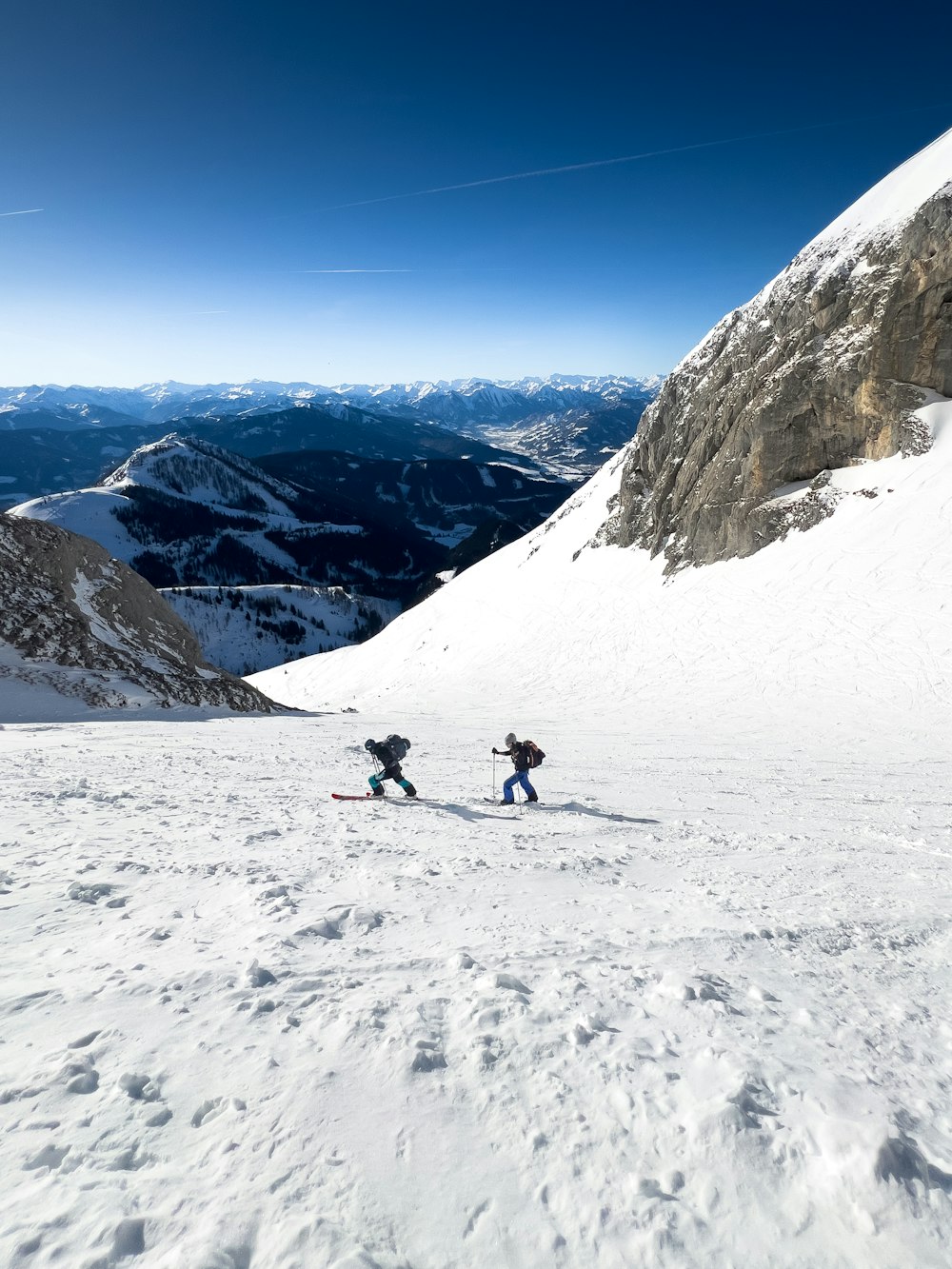 a couple of people riding skis down a snow covered slope