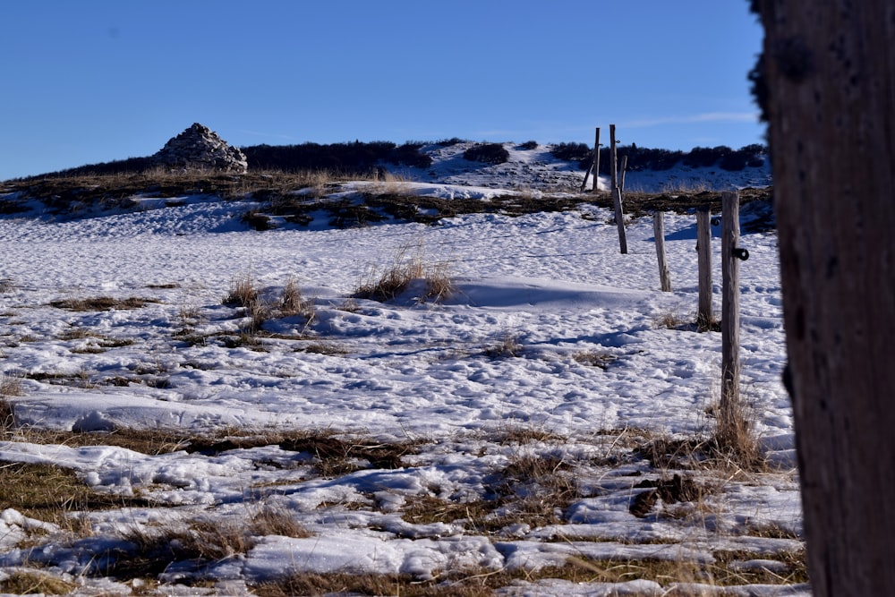 a snow covered field with a hill in the background