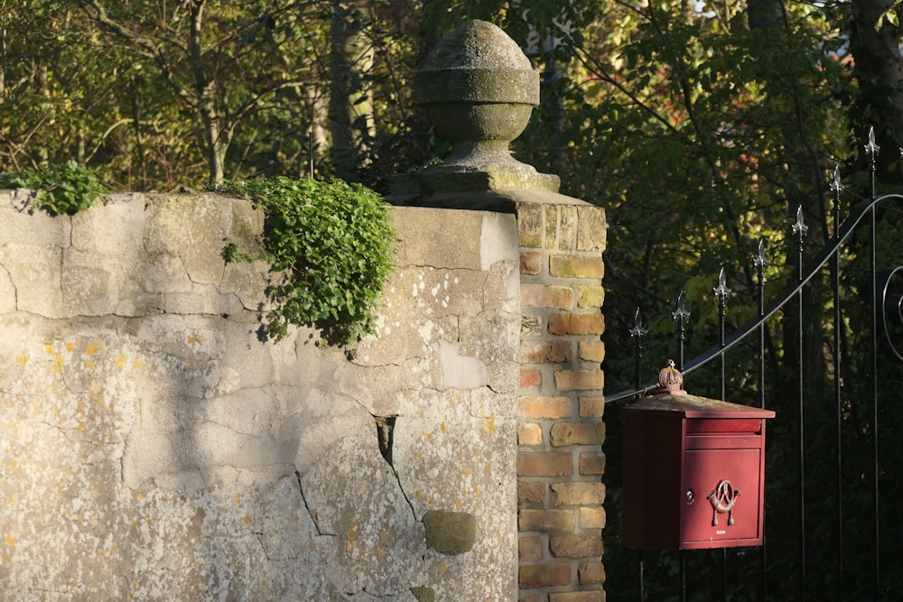 a red mailbox sitting on the side of a brick wall