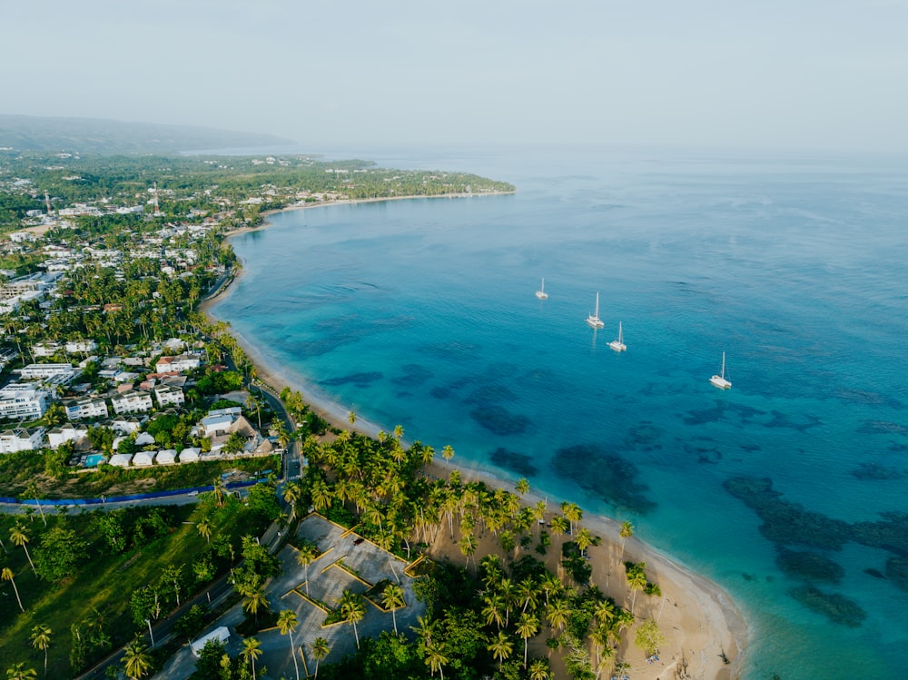 an aerial view of a beach with boats in the water