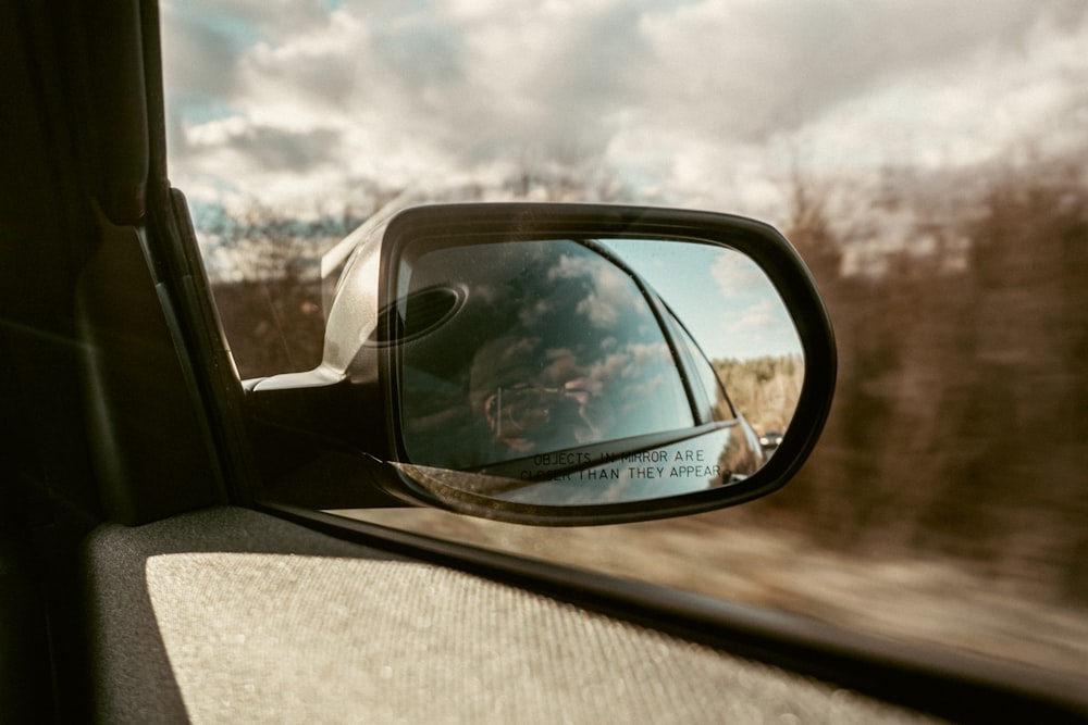 a side view mirror on a car with a sky in the background
