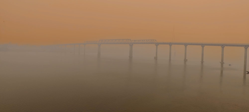 a foggy bridge over a body of water