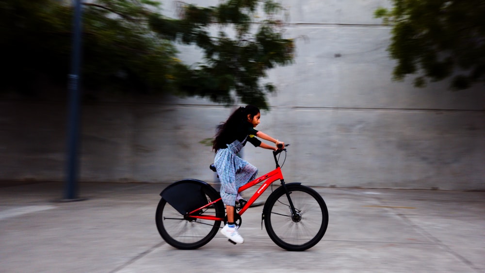a woman riding a red bike down a street