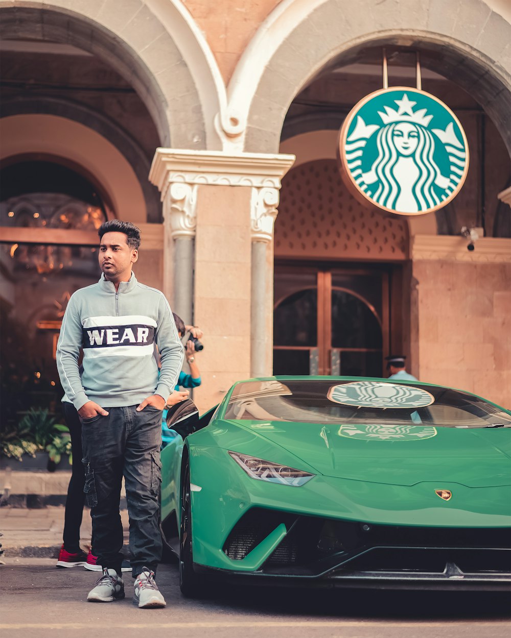 a man standing next to a green sports car