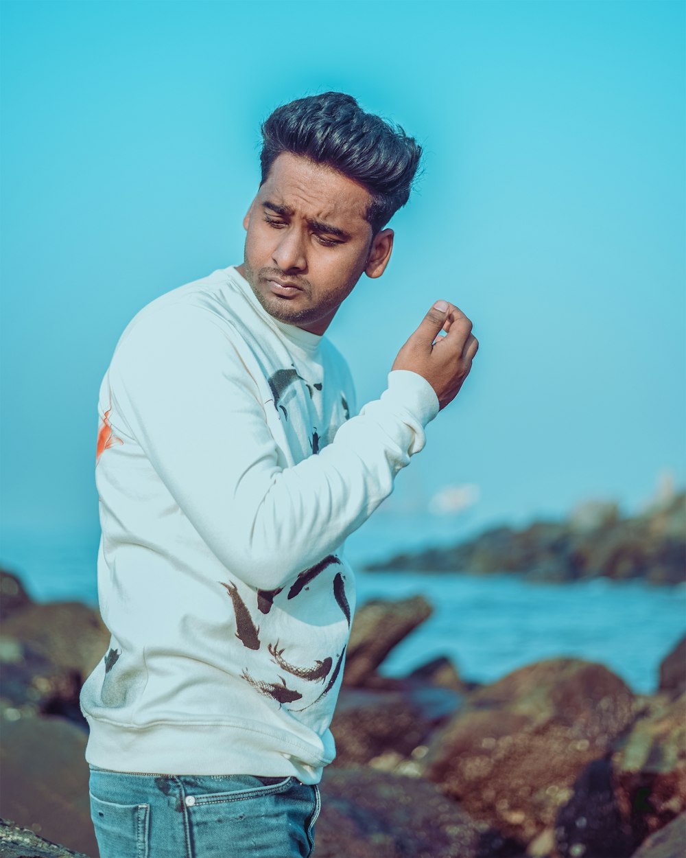 a man standing on a rocky beach next to the ocean