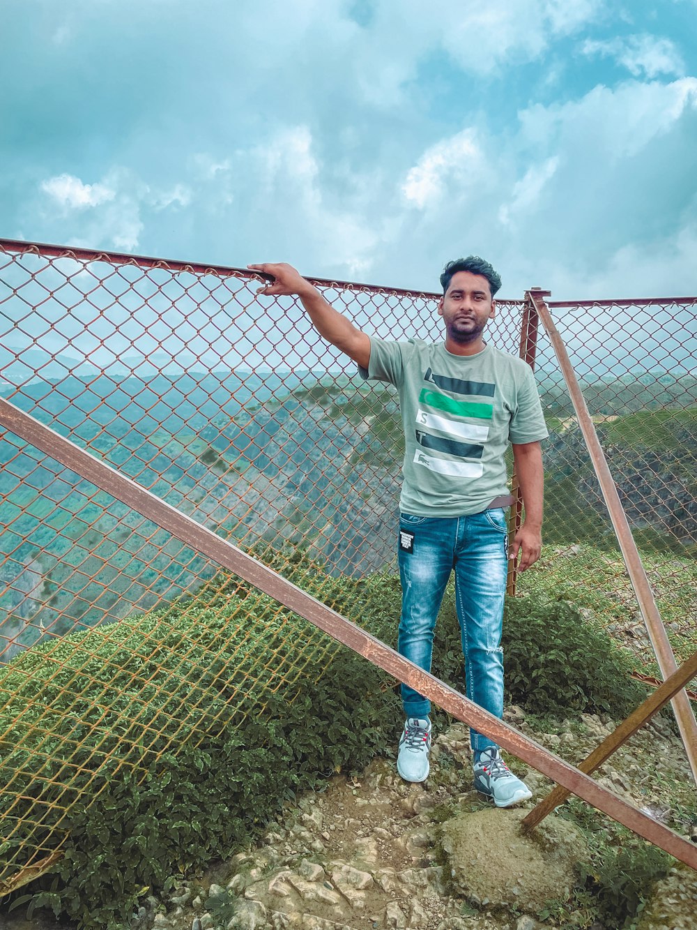 a man standing on top of a mountain next to a fence